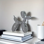 Black and white checkered balloon animal sculpture on a stack of books with a neutral background