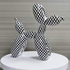 Black and white checkered balloon dog sculpture on a round white platform with a neutral background