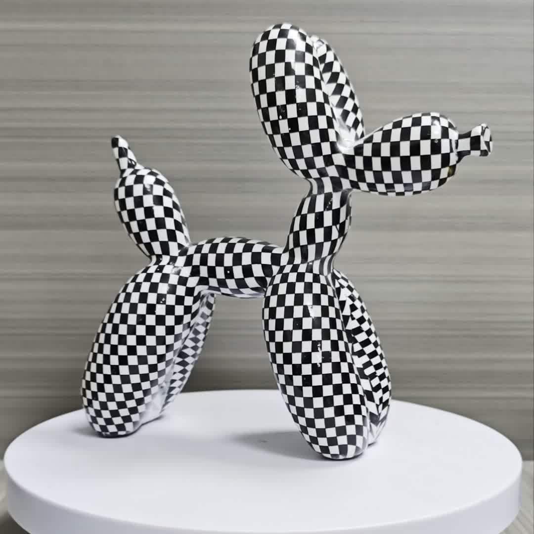 Black and white checkered balloon dog sculpture on a round white platform with a neutral background