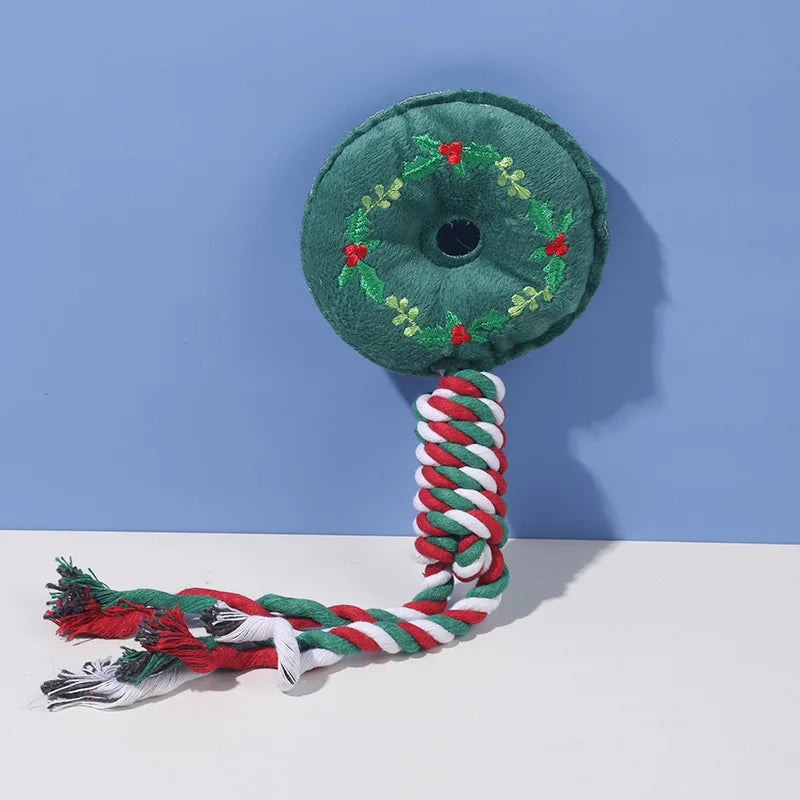 Green dog toy with a wreath design and red, white, and green rope on a blue and white background