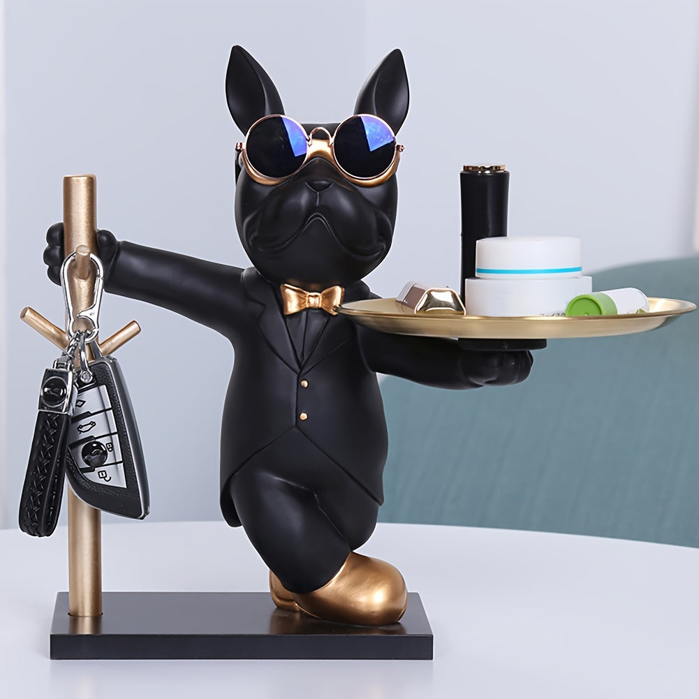 Black dog figurine in a suit holding a tray with items on a white surface.