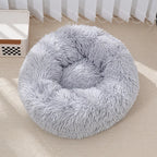 Fluffy gray pet bed on a beige floor with white curtains in the background