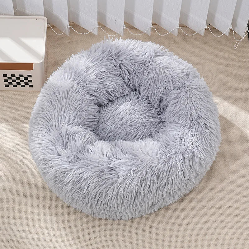 Fluffy gray pet bed on a beige floor with white curtains in the background