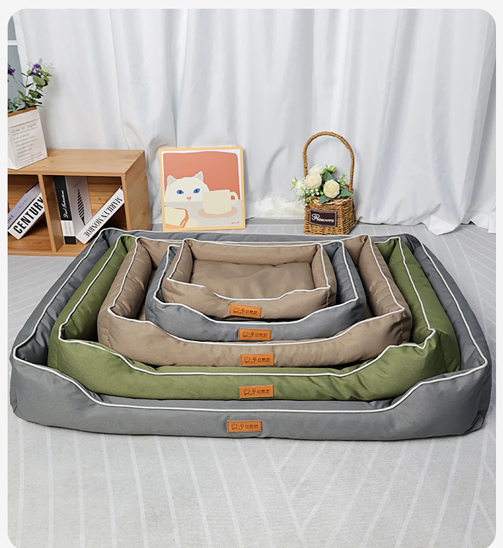 Set of pet beds in green, gray, and beige on a bed with a white curtain background.